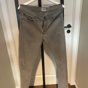 Grå super slim jeans från Edwin - Säljer ett par gråa Edwin ED-88 jeans i super slim fit. Byxorna har klassisk femficksdesign, dragkedjegylf och är tillverkade i ett mjukt bomullstyg med stretch. Perfekta om du gillar en smal och modern siluett.