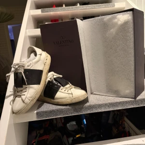 Valentino Garavani vita sneakers strl 44 - Ett par riktigt snygga Valentino Garavani Open I svart och vitt i storlek 44. De är i lite dåligt skick med några få defekter som syns på bilderna. Ny pris ca 6000kr. Hör av dig om du har några frågor