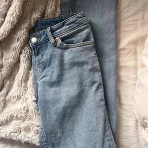 Monki ljusblå jeans, storlek 24 - Säljer ett par ljusblå jeans från Monki med klassisk femficksdesign och snygga kontrastsömmar. Jeansen har låg midja och raka ben, tillverkade i mjukt denimtyg. Perfekt för dig som gillar enkel och clean stil.