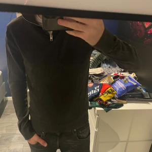 Mörkgrå stickad tröja Jack & Jones - Mörkgrå stickad tröja från Jack & Jones med half zip-dragkedja i halsen. Tröjan har lång ärm och ribbade muddar vid ärmslut och nederkant. Perfekt för lager-på-lager och snygg till jeans.