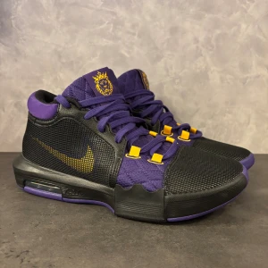 Nike Lebron Witness 8 - Säljer ett par unika Nike Lebron Witness 8 i lila och svart med gula detaljer och lejonmotiv på plösen och hälen. Skorna har snörning, platt sula och mesh-paneler för extra ventilation. Snyggt mönstrad yttersula i lila och svart, perfekt för dig som gillar att sticka ut.
