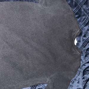 Mörkgrå sweatshirt från Lacoste - Säljer en mörkgrå sweatshirt från Lacoste i klassisk passform. Tröjan har rund halsringning, långa ärmar och det ikoniska gröna krokodilmärket broderat på bröstet. Perfekt för dig som gillar stilren och enkel design.