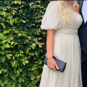 Vit/beige balklänning  - Säljer nu denna fina balklänningen. Superfin vit/beige balklänning med ett blommigt mönster och puffiga korta ärmar. Använd 1 gång. Nypris 5800. Ett hål finns nedtill, finns bild. 