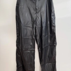 Svarta byxor i faux leather från ONLY - Svarta byxor i faux leather från ONLY i storlek 34/XS med raka ben och klassisk passform. Har använts en del gånger och har ett litet märke på vänster ben. 