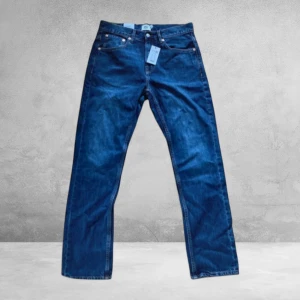 Blå jeans W30 L32 - Snygga blå jeans i klassisk rak modell. Jeansen har midwaist, standard fit och är tillverkade i slitstarkt denim. Perfekta för dig som gillar en enkel och tidlös look. Färgtonen är mörkblå och passformen är normal.