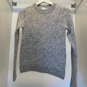 Grå stickad tröja från Zara - Mysig gråmelerad stickad tröja från H&M med rund halsringning och ribbade muddar vid ärmslut och nederkant. Perfekt för lager-på-lager och chill dagar. Klassisk passform och långärmad modell.