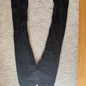 Svarta slim fit jeans från nudie w29 L32 - Svarta jeans från nudie med klassisk femficksdesign och smal passform. Jeansen har en enkel look med svarta sömmar och silverfärgade knappar. Perfekta för dig som gillar en stilren och tajt siluett.