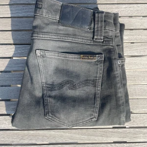 Nudie jeans - Pris kan diskuteras!!Snygga svarta/gråa jeans från Nudie med klassisk femficksdesign och diskret logga på bakfickan. Jeansen har en skinny passform och är tillverkade i mjukt denimtyg. Perfekta för dig som gillar en stilren och modern look.