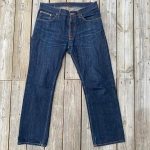 Nudie Jeans Loose Leif Dry Selvage - Säljer dessa sjukt häftiga jeans från Nudie i modellen Loose Leif (32/30) som först släpptes 2016 och försvann runt 2019. Relativt sällsynta alltså. Modellen är vidare/loose fit med en benöppning som påminner mer om regular jeans, går alltså att använda för den som inte gillar när byxorna täcker för mycket av skorna! Mycket fint skick, använda sparsamt och har med tiden börjat få fina fades som kan ses i bilderna. Mått ses nedan✅  Midja: 42-43 cm Ytterbenslängd: 99-100 cm Benöppning: 21-21,5 cm 