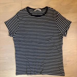 Randig t-shirt från Mango - Snygg t-shirt från mango med marinblå och vita horisontella ränder. Klassisk rund halsringning och korta ärmar. Gjord i mjuk bomull som känns skön mot huden.