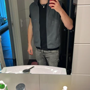 Mörkgrå fleeceväst med dragkedja - Snygg mörkgrå fleeceväst med hög krage och hel dragkedja framtill. (Oanvänd då den är för liten) Västen har två praktiska fickor med dragkedja på sidorna och en stilren, enkel design utan mönster. Perfekt att slänga på över en t-shirt för extra värme eller bara för att slänga på en touch på din outfit, fungerar till nästintill allt, tveka inte på att höra av dig vid frågor eller funderingar!
