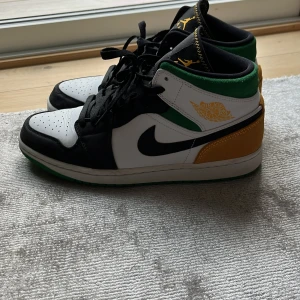 Nike Air Jordan 1 Mid svart/vit/grön/gul - Nike Air Jordan 1 Mid i svart, vitt, grönt och gult. Klassisk siluett med svart Swoosh, perforerad tåbox och snörning. Gula detaljer på häl och logga, samt grön vadderad krage. Ovandel i skinn och syntet. Perfekta för dig som vill sticka ut med din sneakerstil. Storlek 44,5. Pris kan diskuteras. Skick 10/10