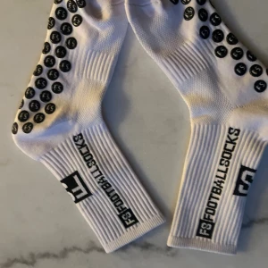 Vita F3 Footballsocks med grepp - Säljer ett par vita F3 Footballsocks med svarta grepp på undersidan för extra fäste. Strumporna har ribbade skaft och svart logga längs sidan. Perfekta för fotbollsträning eller match. Materialet är mjukt och andas bra.