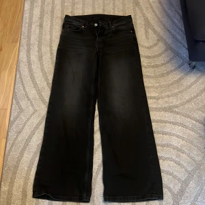 Svarta wide jeans 25/30 - Svarta jeans med breda ben och klassisk femficksdesign. Snyggt raka och vida i modellen, perfekta för en avslappnad men trendig look. Jeansen har hällor för bälte och stängs med knapp och dragkedja. Tillverkade i jeansmaterial.