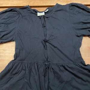 Marinblå blus från Gina Tricot - Marinblå blus från Gina Tricot med puffiga ärmar och rosetter framtill. Klänningen har en avslappnad passform och är gjord i mjuk bomull, perfekt för en chill och stilren look. Säljer p.g.a att jag inte använde den och blev snabbt förliten. Kan såklart gå ner till billigare pris!! Jag har fri frakt på alla mina nuvarande annonser så kika in!!! 