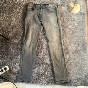 Grå Replay jeans hyperflex. Storlek: 32 32 - Snygga grå jeans från Replay med klassisk femficksdesign och dragkedja. Jeansen har en slim passform och raka ben, tillverkade i mjukt denimtyg som sitter skönt. Perfekta för dig som gillar stilrena och enkla jeans med en modern look.