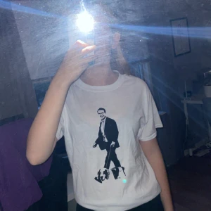 Vit och svart T-shirt med Ulf Kristersson tryck - En vit T-shirt med svart tryck på Ulf Kristersson. Fick av nån kompis på skämt nån gång, aldrig kommit till användning, så i helt nytt skick. Väldigt skönt material och stilren 