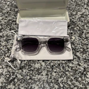 CHIMI 04 silvriga glasögon - Säljer ett par stilrena glasögon från CHIMI med silvriga bågar. Kommer med originalvitt hårt etui och en vit tygpåse med dragsko. Perfekt accessoar för dig som gillar minimalistisk och modern design.