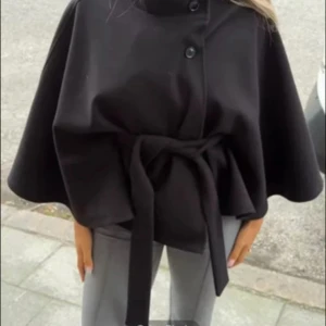 Svart poncho kappa - Säljer en svart kappa med hög krage, knappar framtill och ett snyggt bälte i midjan. Jackan är lite poncho liknande och är super snygg! Vet tyvärr inte vart den är ifrån då lappen är avklippt, men kom gjärna med prisförslag 💕💕