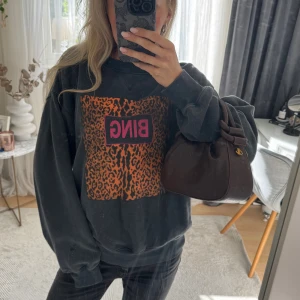 Anine bing sweatshirt med leopardmönster - Cool sweatshirt från Anine Bing med stort leopardmönster i orange och svart framtill samt rosa BING-tryck. Oversized passform och långa ärmar. 