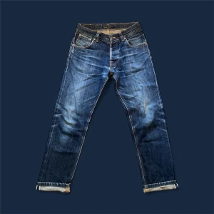 Nudie Jeans Steady Eddie Dry Selvage 30/32 – Grymma fades, välskött skick - Säljer ett par Nudie Jeans Steady Eddie Dry Selvage i storlek 30/32. Jeansen har utvecklat riktigt feta fades över tid som ger dem en unik karaktär och en grym vintage-look. 	•	Modell: Steady Eddie 	•	Storlek: 30/32 	•	Midja: 38,5 cm 	•	Längd: 95 cm 	•	Nedre byxöppning: 18 cm 	•	Skick: Väldigt bra – enda lilla defekten är en diskret lagning i grenen som knappt syns.  Perfekta jeans för den som gillar rådenim med personlighet! 