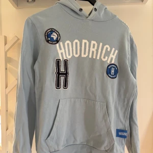 Ljusblå hoodie från Hoodrich XS - Snygg ljusblå hoodie från Hoodrich i storlek XS. Tröjan har broderade patches och tryck framtill, magficka och huva.