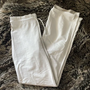 Vita mjukisbyxor - Säljer ett par fräscha vita mjukisbyxor med elastisk midja och snörning. Byxorna har raka ben och är tillverkade i mjukt bomullsmaterial, perfekta för en chill och avslappnad stil. Passar dig som gillar enkel och clean look. Pytteliten fläck.