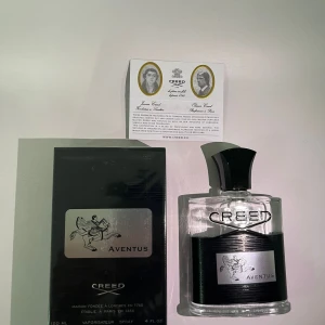 Creed Aventus Eau de Parfum 120ml - Lyxig parfym från Creed, Aventus, i en stilren glasflaska med svart och silverdetaljer. Flaskan rymmer 120 ml och har en svart, elegant kork. Medföljer gör originalkartong och äkthetskort. Perfekt för dig som gillar exklusiva dofter och snygg design.