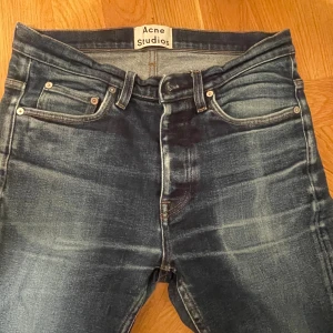 Acne Studios blå jeans Town STR RAW - Snygga blå jeans från Acne Studios, modell Town STR RAW. Jeansen har en klassisk femficksdesign, raka ben och coola slitningar. Tillverkade i bomull med lite stretch för skön passform. Perfekta för dig som gillar stilrena och trendiga jeans.