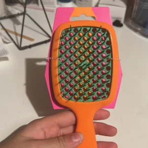 Färgglad hårborste - Ny, färgglad hårborste med orange handtag och grön/rosa borst. Perfekt för daglig användning och passar alla hårtyper. Levereras i originalförpackning och är helt oanvänd. Inga synliga defekter eller slitage.