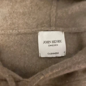Brun hoodie i kashmir från John Henric - Mjuk och lyxig brun hoodie från John Henric i 100% kashmir. Tröjan har huva, långa ärmar och ribbade muddar. Perfekt för dig som vill ha en stilren och bekväm look med exklusiv känsla. Nypris 2700kr obs den e ljusbrun!