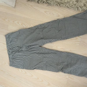 Randiga linnebyxor med snörning - Snygga och luftiga byxor i svartvitt randigt mönster med dragsko i midjan. Perfekta för varma dagar och chill vibes. Tillverkade i mjukt linne som känns skönt mot huden. Avslappnad passform och elastisk midja för extra komfort.