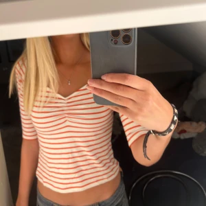 Randig croppad topp med v-ringning - Säljer en vit och röd randig croppad topp med v-ringning och  rynk framtill. Toppen har halvlånga ärmar och är gjord i ett skönt material. Nästintill aldrig använd och perfekt till alla tillfällen. Lappen är av, så vet inte vart den är ifrån eller storleken men den passar mig som brukar ha XS/S 
