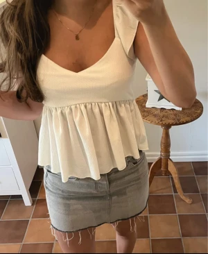 Vit blus med volang - Supersöt vit blus från 157 i storlek S. Blusen har volangdetaljer vid axlarna, v-ringad hals och ett rynkat, flowy fall nedtill. Materialet är lätt strukturerat och känns luftigt, perfekt för varma dagar. Passformen är normal och blusen är ärmlös.