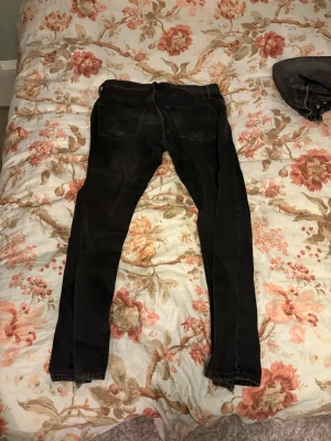 Svarta  jeans storlek 33/34 - Svarta jeans med smal passform och klassisk femficksdesign. Jeansen har en snygg mörk tvätt och raka ben som smalnar av mot ankeln. Perfekt för dig som gillar en stilren look och vill ha jeans som sitter  bekvämt.