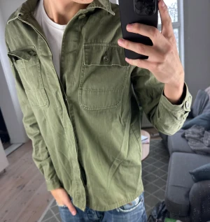 Overhsirt olivgrön  - Trendig och snygg! Saknar en knapp på ena fickan! Mått: A:50cm B:48cm C:42cm D:60cm skriv vid fundering 😊