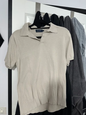 Beige pikétröja från Riley - Snygg beige pikétröja från Riley med klassisk krage och korta ärmar. Storlek L men passar som m/s. Passar mig inte längre och därför jag säljer den. 