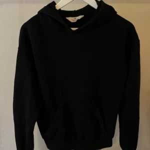Svart hoodie från H&M - En klassisk svart hoodie från H&M med huva och stor magficka framtill. Tröjan har lång ärm och en loose passform 💕
