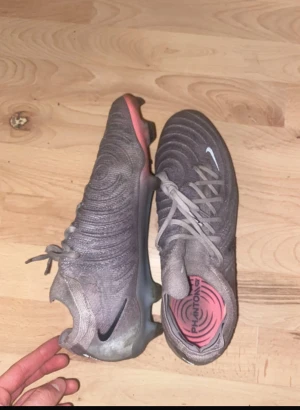 Nike Phantom Vision grå fotbollsskor - Säljer ett par Nike Phantom Vision fotbollsskor i grått med svarta detaljer och rosa innersula. Skorna har snörning och en modern, rundad form med mönstrad ovandel för extra grepp på planen. Perfekta för dig som vill sticka ut på fotbollsplanen.
