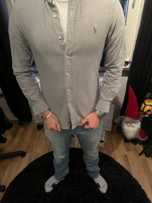 Ljusblå skjorta från Ralph Lauren - Säljer en stilren ljusblå skjorta från Ralph Lauren med klassisk knappstängning och broderad logga på bröstet. Skjortan har lång ärm och är tillverkad i mjuk bomull. Modellen på bilden är 183 och väger 76 kg. Skjortan är i nyskick och är använd max 5 gånger. 