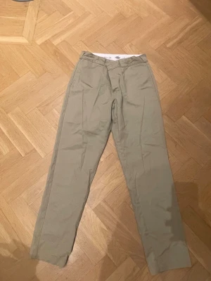 Beige chinos från Dickies x Carlings - Snygga beige chinos från Dickies x Carlings med klassisk rak passform och midwaist. Byxorna har stilren design och är bekväma. Perfekta för dig som gillar enkel och clean stil. W33L32 - passar någon i storlek L