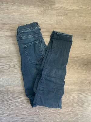 Mörkblå shaping skinny jeans H&M - Mörkblå shaping skinny jeans från H&M med hög midja och klassisk femficksdesign. Jeansen har dragkedja och är tillverkade i stretchigt denim för en tight passform som framhäver siluetten. Perfekta för dig som gillar en smal och modern look.