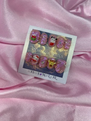 PinkXmasSan (M);ExtraShortOval  - Säljer ett set med handgjorda press-on naglar i rosa med glitter och 3D-sanriomotiv. Naglarna har en extra kort oval form och dekoreras med rhinestones och swirl-mönster. Perfekt för dig som vill ha unika och kreativa naglar.M: 16 mm, 12 mm, 12,5 mm, 11,5 mm, 10 mm 