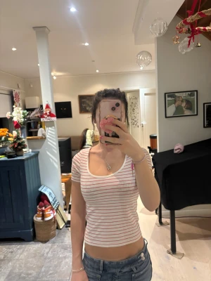 Vit och röd randig croppad topp - Säljer en vit croppad topp med röda ränder och rundad halsringning. Toppen har korta ärmar och sitter tight mot kroppen