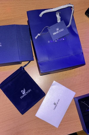 Swarovski Dancing Swan halsband - Snyggt halsband från Swarovski med ett hängsmycke i form av en svan, dekorerat med blå och glittriga kristaller. Kedjan är rhodinerad i silverfärg och smycket levereras i originalförpackning med påse och certifikat. Perfekt för dig som gillar eleganta detaljer och exklusiv design.