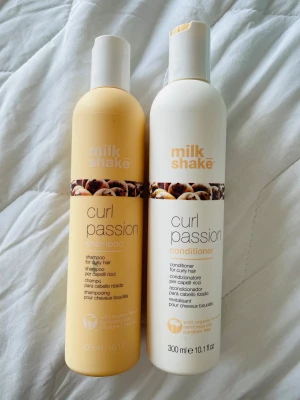 Milk Shake Curl Passion duo 300ml - Två flaskor Milk Shake Curl Passion, en schampo och en balsam för lockigt hår. Schampot är ljusgult och balsamet vitt, båda med tryckt logga och motiv av nötter. Innehåller ekologiska oljor från Amazonas och är fri från parabener och sulfater.