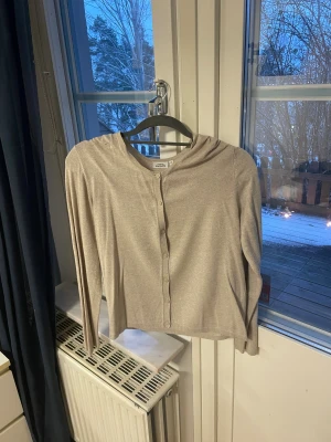 Beige kofta från KappAhl, storlek M - Snygg beige kofta från KappAhl i storlek M. Den har rund hals, långa ärmar och knappar framtill. Materialet känns mjukt och lätt, perfekt för lager-på-lager. Enkel och stilren design som funkar till många olika looks.