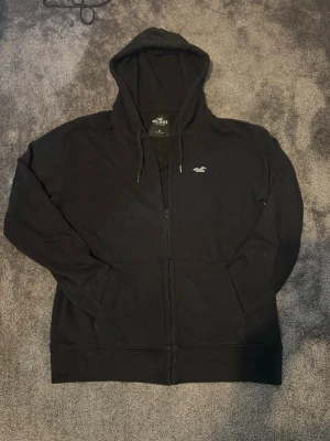 Hollister zip hoodie - Svart hollister zip hoodie i size M men hollister text på armen som är inte så vanligt. Väldigt bra skick inget tecken på användning. Väldigt snygg och basic. Skön och varm. Priser kan diskuteras. Skickar snabbt!