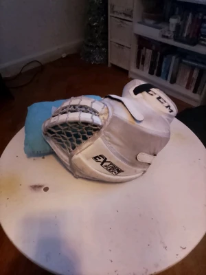 Vita CCM Extreme Flex hockeyhandskar - Säljer ett par vita CCM Extreme Flex hockeymålvaktshandskar med svart logga och nätficka. Handskarna har en robust design med breda skyddspaneler och justerbara remmar. Perfekta för dig som vill ta ditt målvaktsspel till nästa nivå.