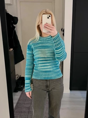 Vintage blå stickad tröja Peak Performance - Supersnygg vintage stickad tröja från Peak Performance i blått och vitt med randigt mönster. Stickad i 100% bomull. Den är från 80-90 talet så modellen säljs inte längre. Tröjan har ribbade muddar, rund hals och lång ärm. Perfekt för dig som vill ha en färgklick i garderoben!